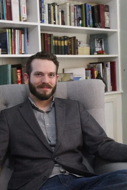 Erik Marsh seated beside a bookshelf